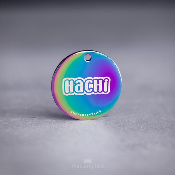 Rund namnbricka, idbricka i regnbågens olika färger graverad med namnet Hachi