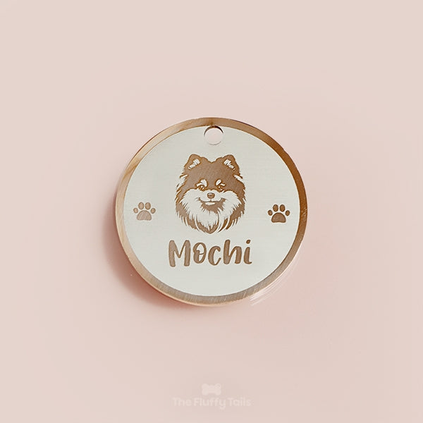 Rund egendesignad ID-bricka i roséguld med pomeranianhund, två tassar på varje sida och hundens namn