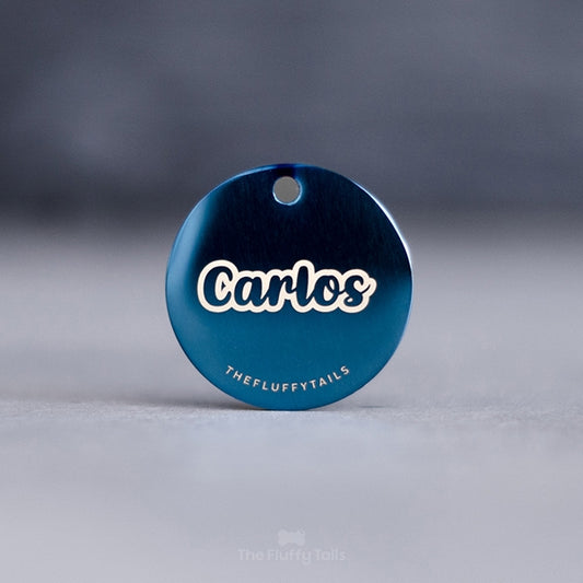 Blå, rund ID-bricka med hundens namn med typsnitt i skrivstil