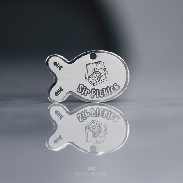 Fiskformad silvrig namnbricka med egen design och gravyr på två fiskben och en katt som håller i en pizza, sittandes i pizzalåda