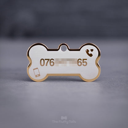 Guldig, hundbensformad namnbricka med telefonnummer, ikon på 2 telefoner och ett hjärta på en ljus bakgrund