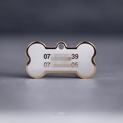 Guldig, hundbensformad namnbricka med 2 telefonnummer på en ljus bakgrund