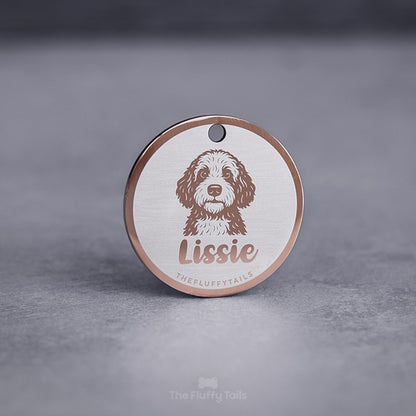 Rund namnbricka, id-bricka, i roséguld med ljus bakgrund, graverad med bild på en portugisiskt vatten hund och hundens namn i skrivstil