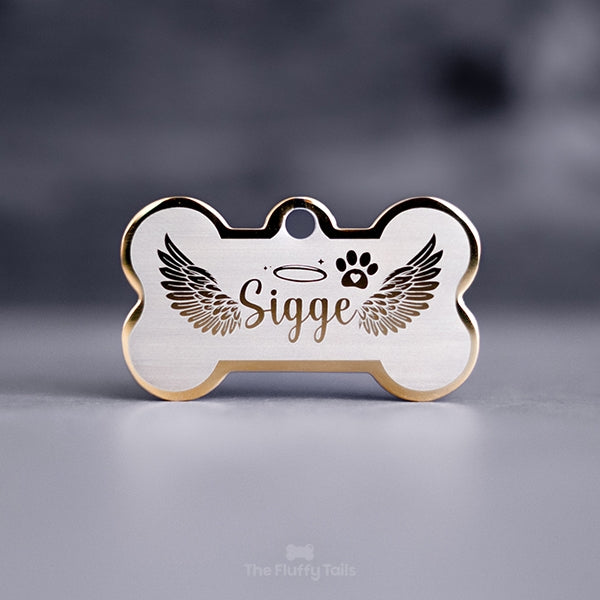 Guldfärgad namnbricka, minnesbricka i hundbensform till minne av hund eller katt, graverad med vingar och tass med ett hjärta