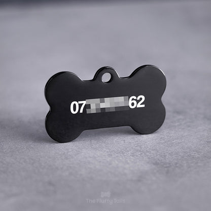 Baksidan på en svart, hundbensformad ID-bricka, graverad med telefonnummer