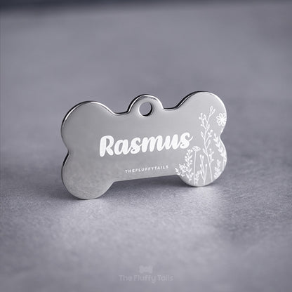 Silvrig, hundbensformad namnbricka graverad med somrig design, vita växter och namn