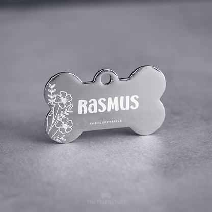 Silvrig, hundbensformad namnbricka graverad med somrig design, vita blommor och hundens namn