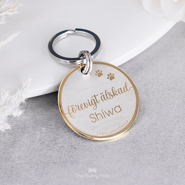 Rund nyckelring av rostfritt stål och unik design, med texten förevigt älskad och djurets namn, till minne av ett husdjur som har gått bort