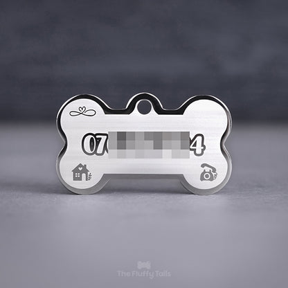 Silvrig, hundbensformad namnbricka med personlig gravyr. Telefonnummer, ikoner av hus, klassisk telefon och evighetssymbol med hjärta