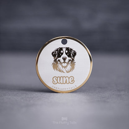 Guldig, rund namnbricka med ljus bakgrund och gravyr på en berner sennen hund