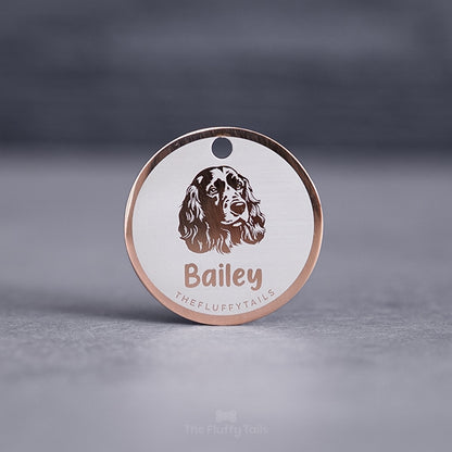 Rund namnbricka av rostfritt stål i färgen roséguld med egen design och personlig gravyr en hundrasen cocker spaniel samt hundens namn