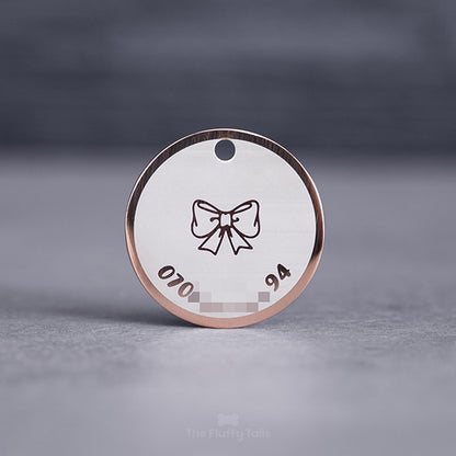 Rund namnbricka av rostfritt stål i färgen roséguld, med egen design, graverad med en rosett och telefonnummer till ägaren, passar både hundar och katter