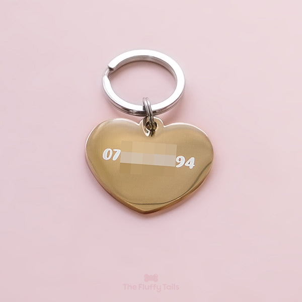 Baksidan av en guldig, hjärtformad ID-bricka, namnbricka, graverad med telefonnummer