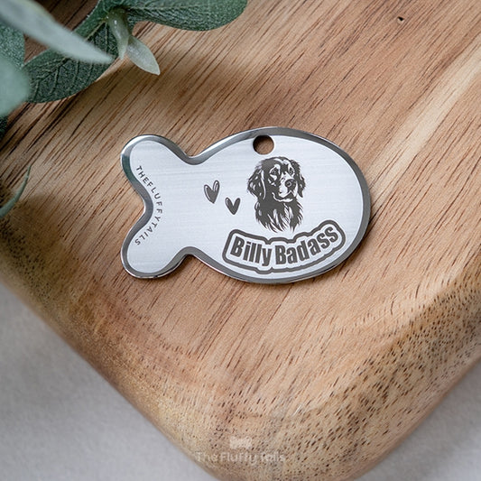 Silvrig namnbricka av rostfritt stål i fiskform, graverad med en golden retriever och hundens namn. Passar både hund och katt. 