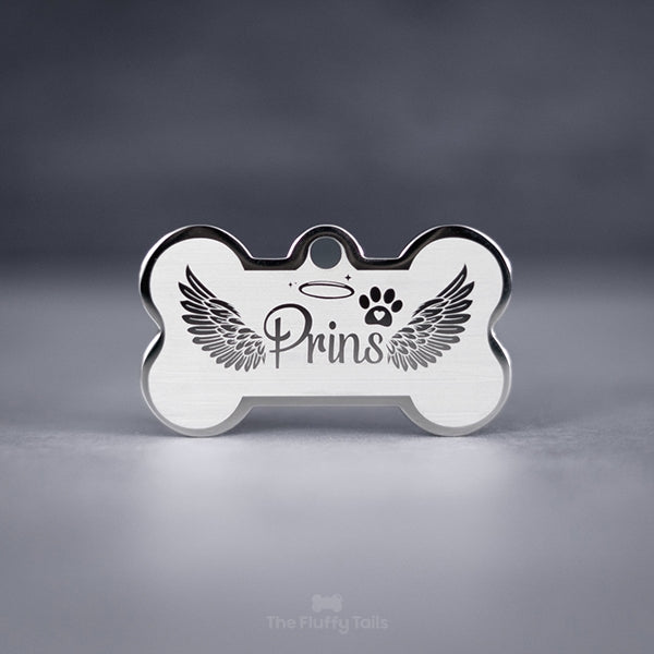 Silvrig minnesbricka i hundbensform av rostfritt stål, designad med änglavingar och graveras med hundens, kattens eller djurets namn. Perfekt att användas som nyckelring.