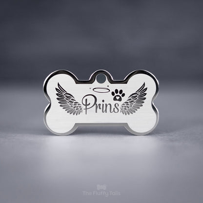 Silvrig minnesbricka i hundbensform av rostfritt stål, designad med änglavingar och graveras med hundens, kattens eller djurets namn. Perfekt att användas som nyckelring.