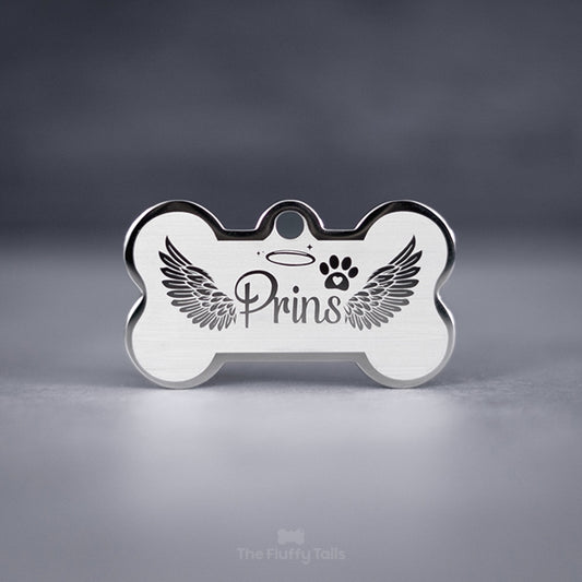Silvrig minnesbricka i hundbensform av rostfritt stål, designad med änglavingar och graveras med hundens, kattens eller djurets namn. Perfekt att användas som nyckelring.