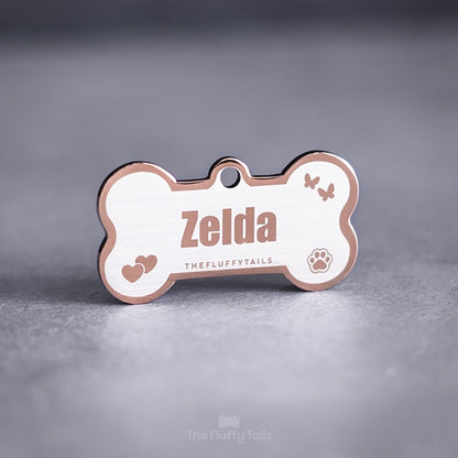 Hundbensformad namnbricka av rostfritt stål i färgen roséguld med egen design och gravyr med fjärilar, hjärtan, tassavtryck och hundens eller kattens namn.