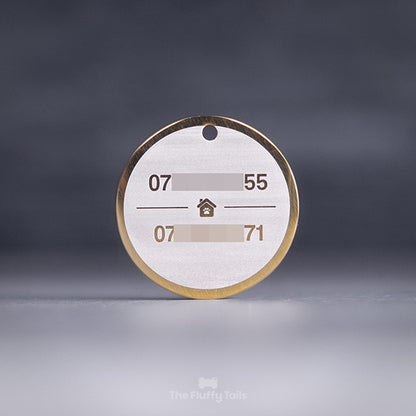 Rund, guldig namnbricka för hund och katt, graverad med två telefonnummer och ett hus i mitten.