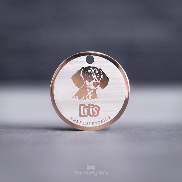 Rund namnbricka i roséguld, för både hund och katt. Graverad med personlig gravyr och egen design på en tax och hundens namn i ett lekfullt typsnitt.
