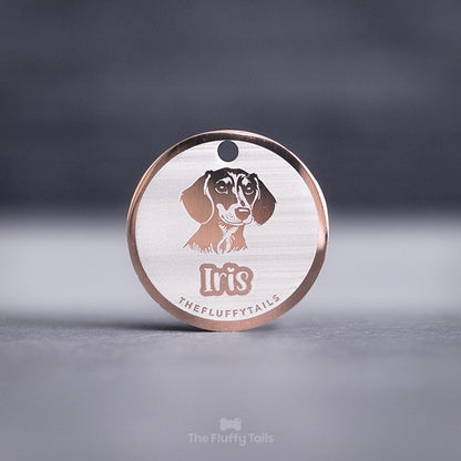 Rund namnbricka i roséguld, för både hund och katt. Graverad med personlig gravyr och egen design på en tax och hundens namn i ett lekfullt typsnitt.