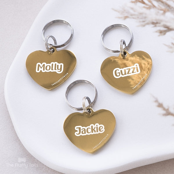 Tre guldiga, hjärtformade namnbrickor, graverade med namn