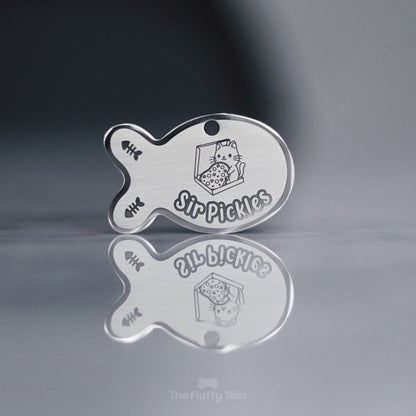 Fiskformad silvrig namnbricka med egen design och gravyr på två fiskben och en katt som håller i en pizza, sittandes i pizzalåda