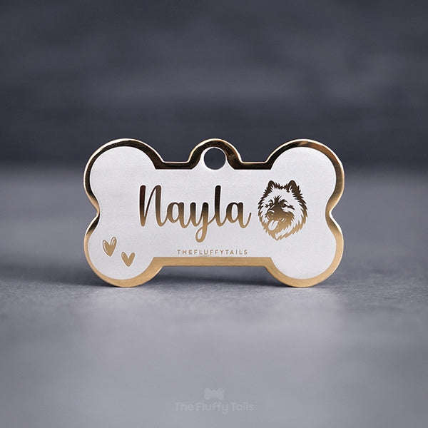 Hundbensformad guldig namnbricka, graverad med namn i skrivstil, ikoner på två handritade hjärtan och en hund av hundrasen eurasier