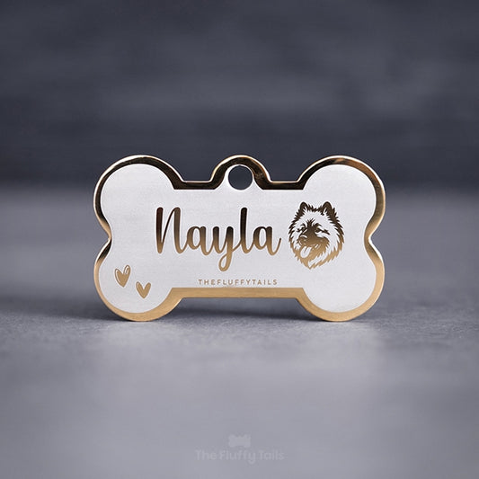 Hundbensformad guldig namnbricka, graverad med namn i skrivstil, ikoner på två handritade hjärtan och en hund av hundrasen eurasier