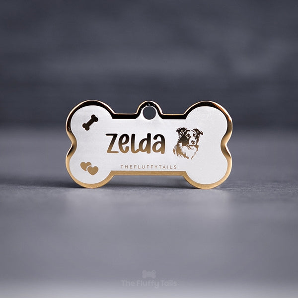 Hundbensformad guldig namnbricka, graverad med namn i handskriven typsnitt, ikoner på ett tuggben, hjärtan och en hund av hundrasen miniature australian shepard