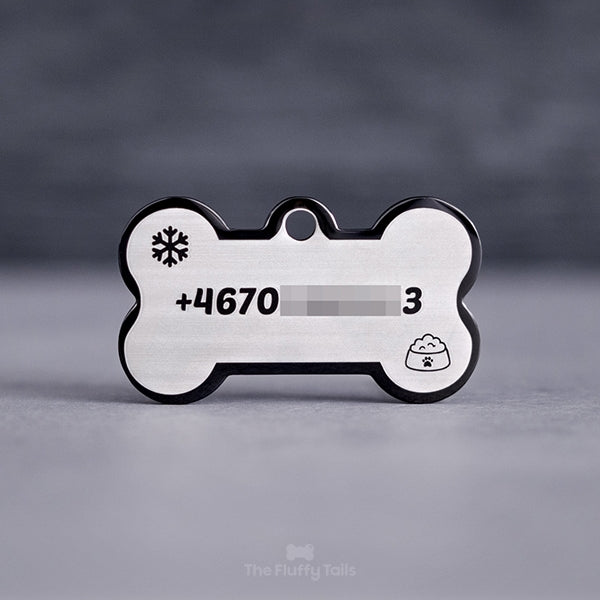 Hundbensformad svart namnbricka, graverad med telefonnummer, snöflinga och en hundmatskål.