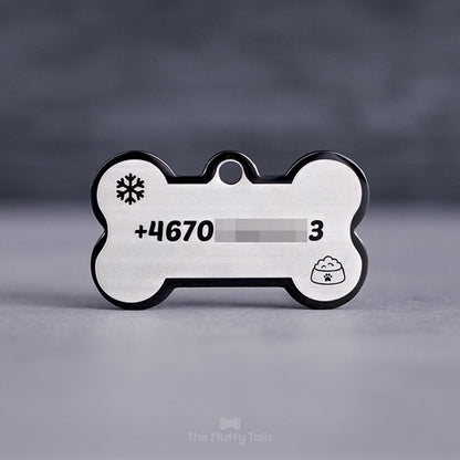 Hundbensformad svart namnbricka, graverad med telefonnummer, snöflinga och en hundmatskål.