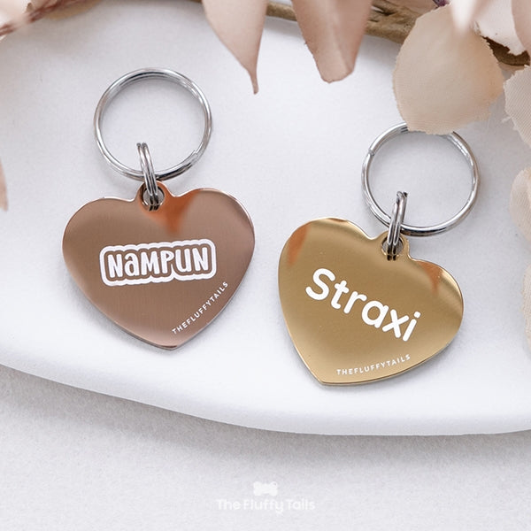 Två hjärtformade namnbrickor i guld och roséguld, graverade med djurets namn. Passar hundar och katter.