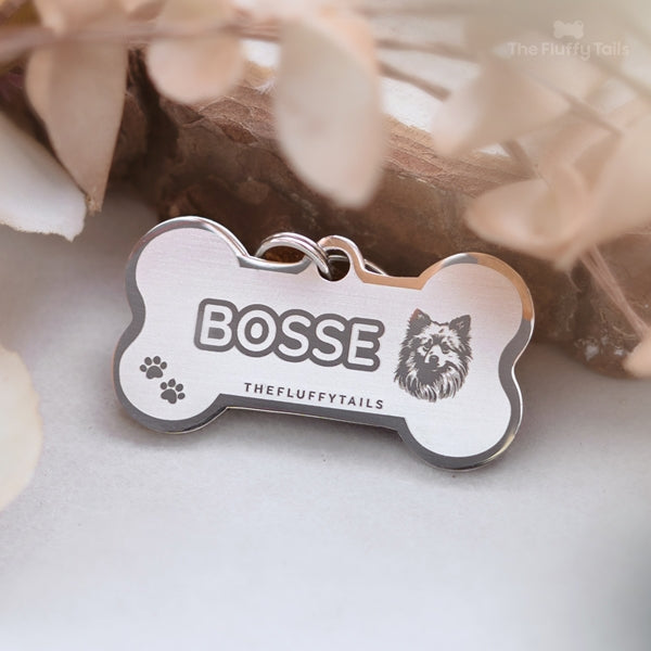 Silvrig hundbensformad namnbricka av rostfritt stål, graverad med hundens namn, tassavtryck och en spetshund