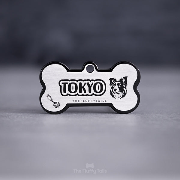 Svart hundbensformad namnbricka av rostfritt stål, graverad med hundens namn, en border collie och repboll