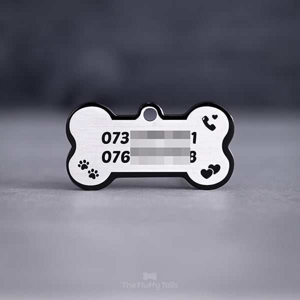 Svart hundbensformad namnbricka av rostfritt stål, graverad med två telefonnummer, tassar, dubbelhjärtan och en telefonlur