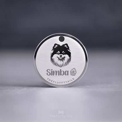 Silvrig rund namnbricka, graverad med en pomeranian, cupcake och hundens namn. Tillverkad av rostfritt stål med spegel polering och personlig gravyr