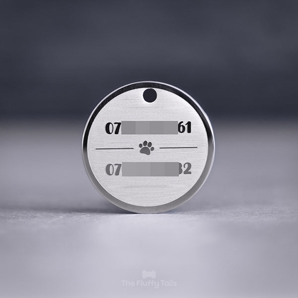 Rund, silvrig namnbricka av rostfritt stål, graverad med två telefonnummer till hundägarna och en tass i mitten, passar både hund och katt