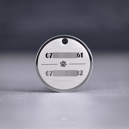 Rund, silvrig namnbricka av rostfritt stål, graverad med två telefonnummer till hundägarna och en tass i mitten, passar både hund och katt