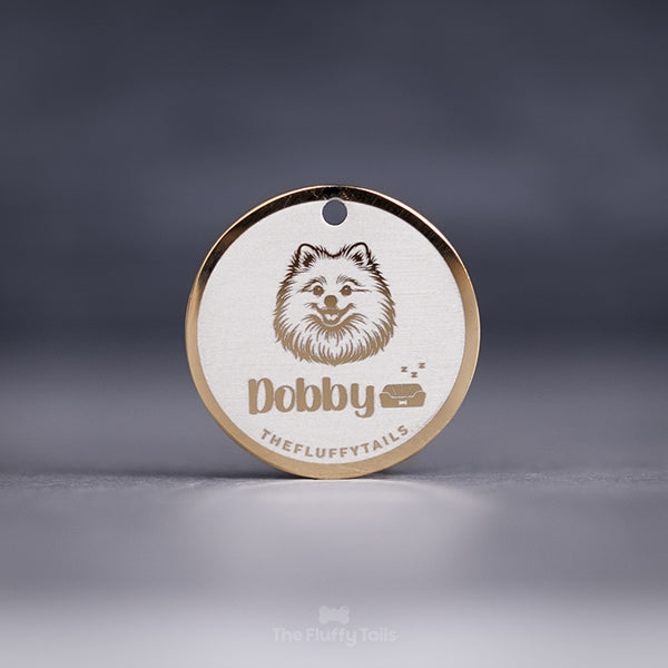 Rund, guldig namnbricka av rostfritt stål, graverad med en pomeranian, hundens namn och en hundbädd