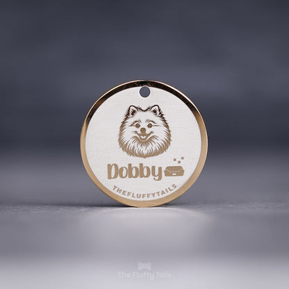 Rund, guldig namnbricka av rostfritt stål, graverad med en pomeranian, hundens namn och en hundbädd