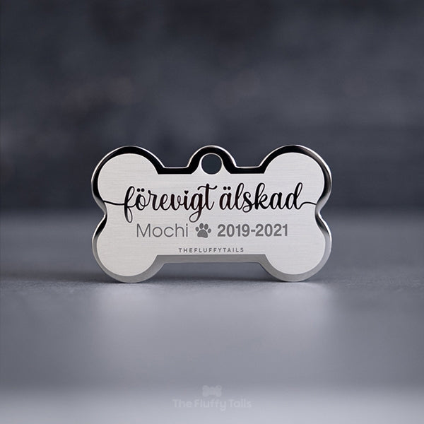 Hundbensformad, silvrig minnesbricka med texten "Förevigt älskad", djurets namn samt årtal. Till minne av ett husdjur, hund, katt som har gått bort.