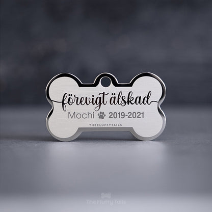 Hundbensformad, silvrig minnesbricka med texten "Förevigt älskad", djurets namn samt årtal. Till minne av ett husdjur, hund, katt som har gått bort.