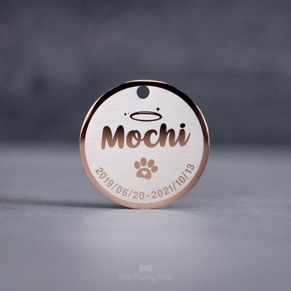 Rund minnesbricka i roséguld med djurets namn, tassavtryck och datum. Kan användas som nyckelring. Till minne av ett husdjur, hund eller katt som har gått bort.