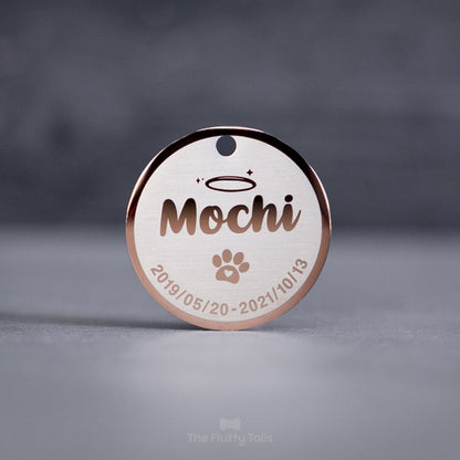 Rund minnesbricka i roséguld med djurets namn, tassavtryck och datum. Kan användas som nyckelring. Till minne av ett husdjur, hund eller katt som har gått bort.