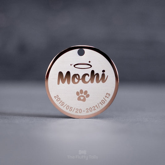 Rund minnesbricka i roséguld med djurets namn, tassavtryck och datum. Kan användas som nyckelring. Till minne av ett husdjur, hund eller katt som har gått bort.