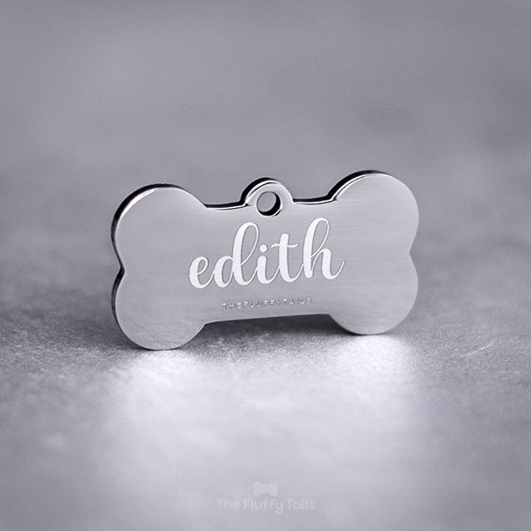 Silvrig hundbensformad ID-bricka, namntag för hund och katt, av rostfritt stål med spegelpolering. Graverad med djurets namn i skrivstil.