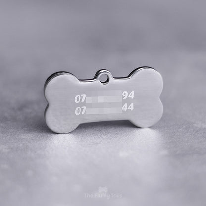 Silvrig, hundbensformad namnbricka av rostfritt stål, graverad med två telefonnummer uppdelade på två rader