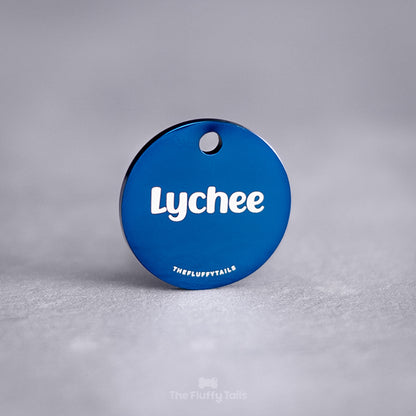 Blå, rund namnbricka av rostfritt stål med personlig gravyr. ID-brickan graveras med djurets namn och passar både hund och katt.