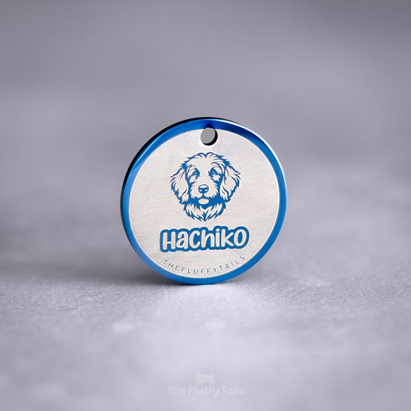 Blå, rund namnbricka av rostfritt stål med egen design. Namnbrickan är graverad med hundens namn och motiv på en hund av rasen goldendoodle.